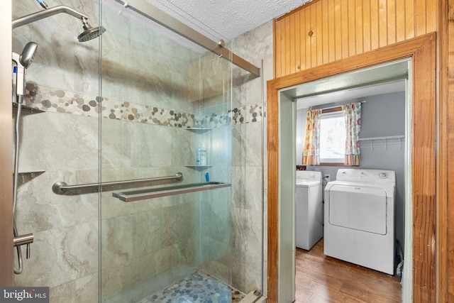 bathroom with a textured ceiling, an enclosed shower, independent washer and dryer, hardwood / wood-style floors, and toilet