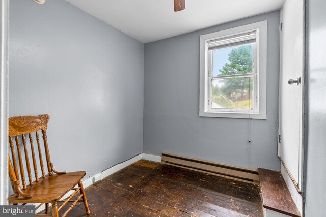 unfurnished room with dark wood-type flooring, a baseboard heating unit, and ceiling fan