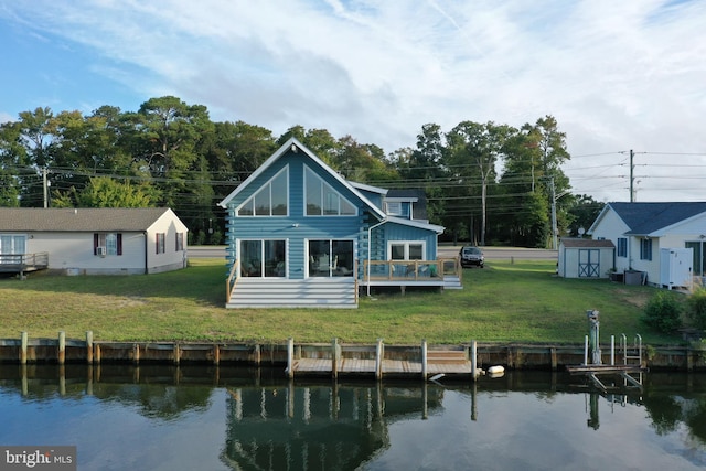 back of property with a water view, a yard, and a storage unit