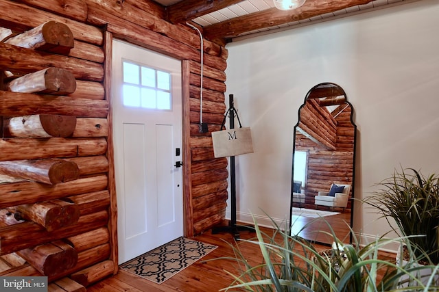 entrance foyer with rustic walls, hardwood / wood-style floors, and beam ceiling