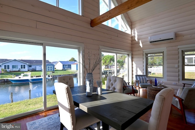 sunroom with a wall unit AC, lofted ceiling with beams, plenty of natural light, and a water view