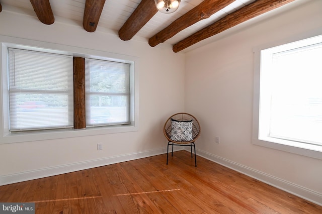 unfurnished room featuring light hardwood / wood-style floors, a healthy amount of sunlight, and beam ceiling