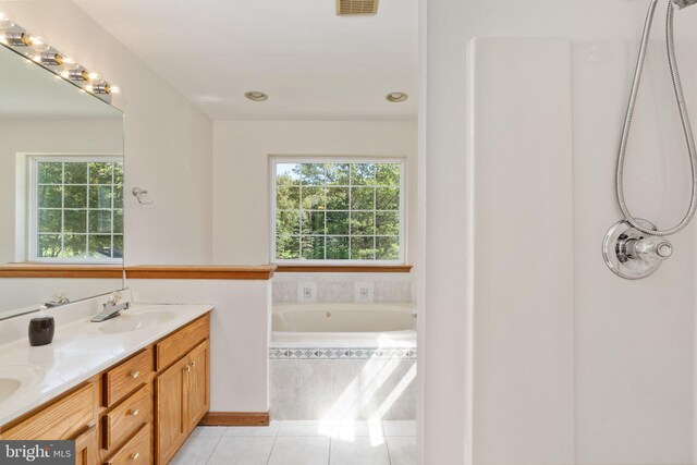 bathroom with tiled tub, vanity, and tile patterned flooring