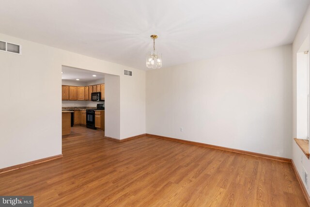 unfurnished living room with a notable chandelier and light wood-type flooring