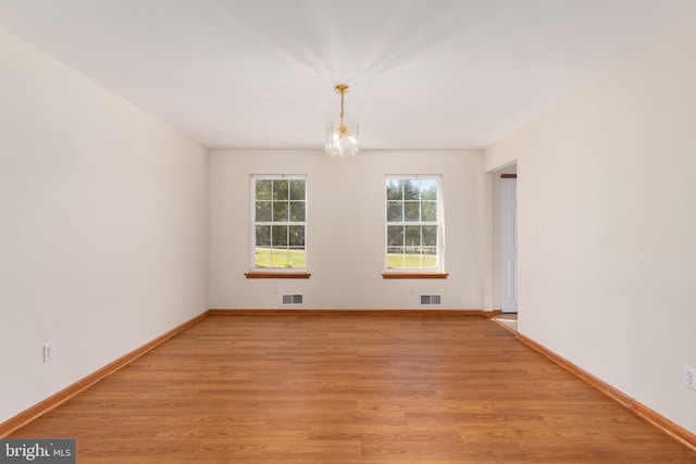 spare room featuring light hardwood / wood-style flooring and a chandelier