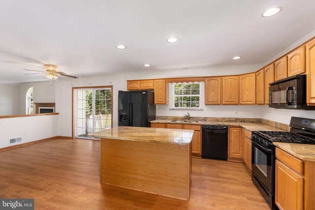 kitchen with ceiling fan, sink, a kitchen island, light hardwood / wood-style flooring, and black appliances