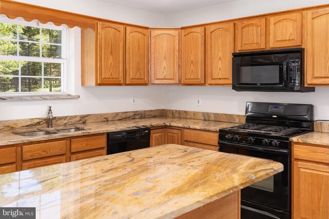 kitchen with black appliances, light stone counters, and sink