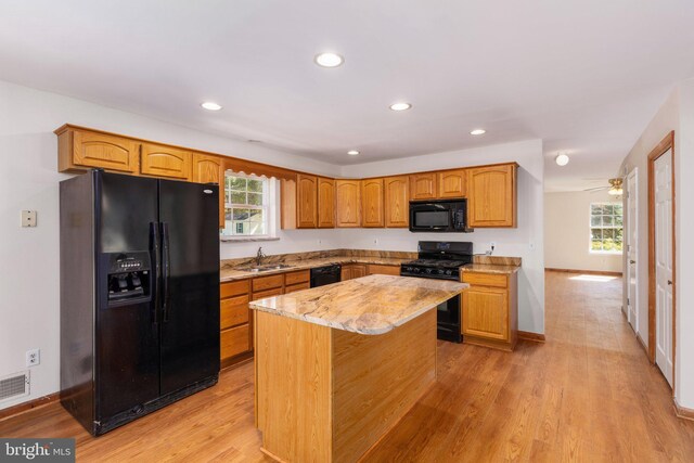 kitchen with a healthy amount of sunlight, black appliances, a kitchen island, and sink