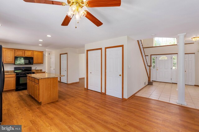 kitchen with ceiling fan, a kitchen island, light hardwood / wood-style flooring, and black appliances