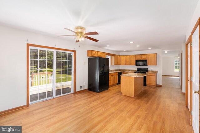 kitchen featuring black appliances, a center island, ceiling fan, and a wealth of natural light