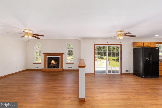 unfurnished living room featuring a wealth of natural light, ceiling fan, and light wood-type flooring