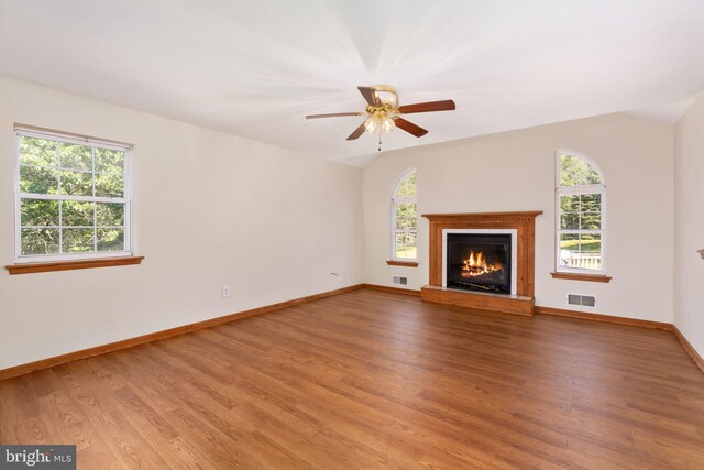 unfurnished living room with a wealth of natural light, ceiling fan, and wood-type flooring