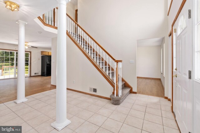 foyer entrance featuring light wood-type flooring, ceiling fan, and ornate columns