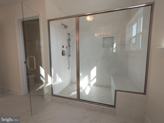 bathroom with a shower with door and toilet