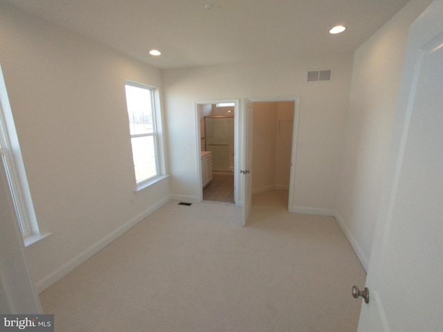 unfurnished bedroom featuring light colored carpet and ensuite bath