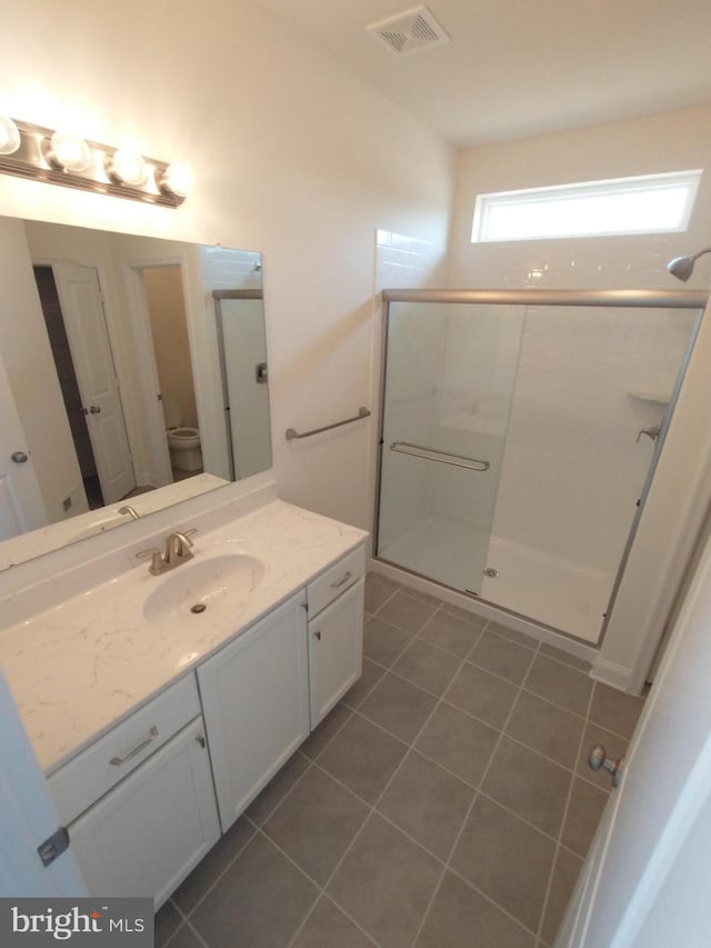 bathroom with walk in shower, vanity, toilet, and tile patterned flooring