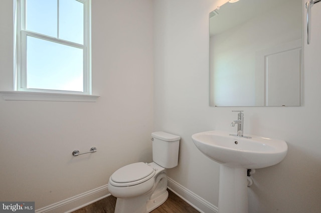 half bathroom featuring baseboards, toilet, and wood finished floors
