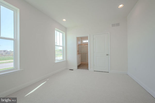 unfurnished bedroom featuring carpet flooring, baseboards, visible vents, and multiple windows