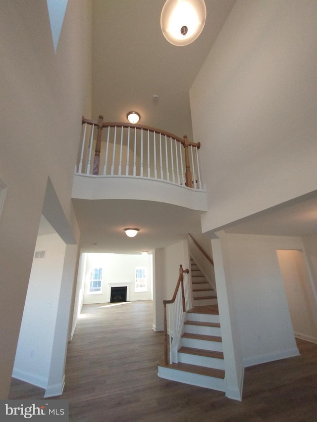 stairway with hardwood / wood-style flooring and a towering ceiling