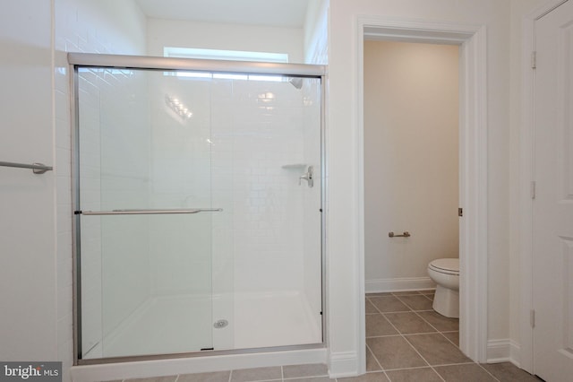 bathroom featuring toilet, baseboards, a shower stall, and tile patterned flooring