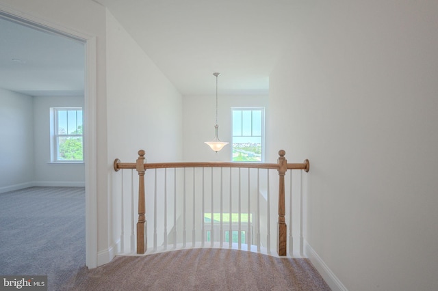 hallway featuring carpet floors, baseboards, and an upstairs landing