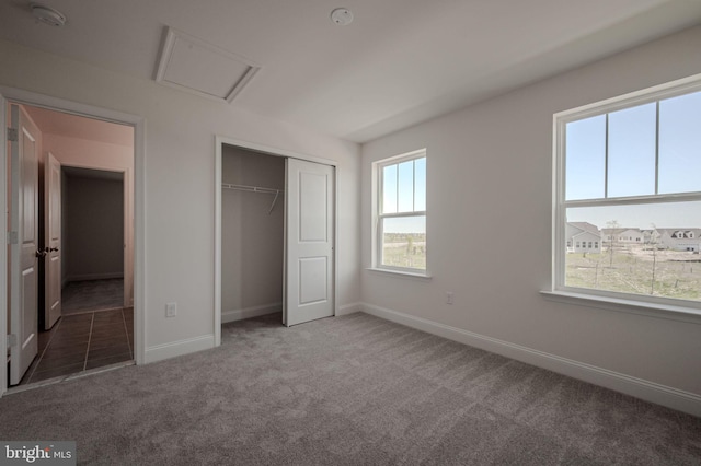 unfurnished bedroom with baseboards, carpet, a closet, and attic access