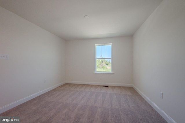 spare room with visible vents, baseboards, and light carpet