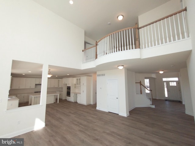 unfurnished living room featuring dark wood-type flooring and a high ceiling