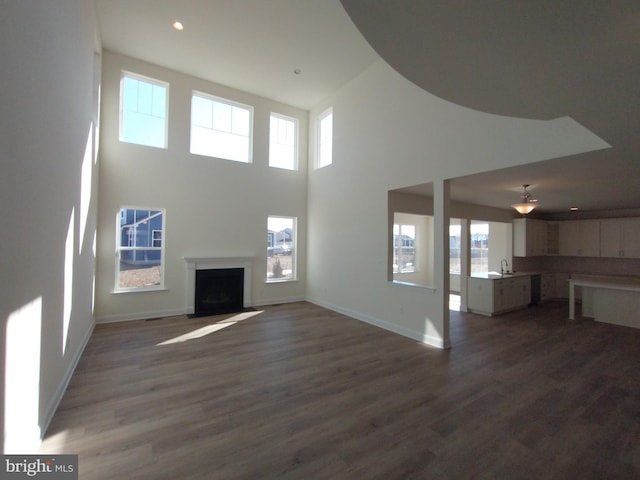 unfurnished living room with a towering ceiling and dark hardwood / wood-style flooring