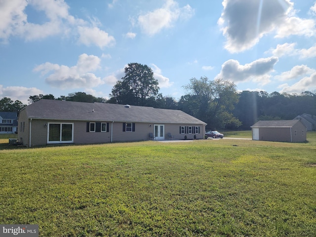 rear view of property featuring a lawn and an outbuilding