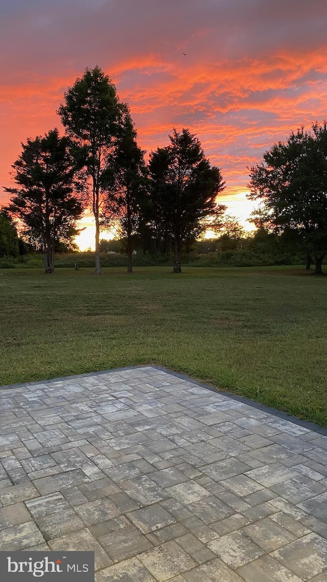 patio terrace at dusk featuring a yard