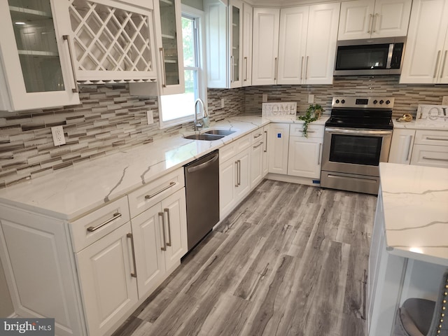 kitchen featuring light stone countertops, stainless steel appliances, sink, and white cabinetry