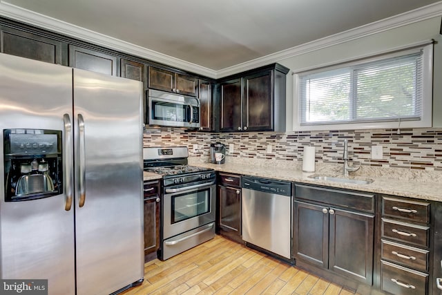 kitchen with dark brown cabinetry, ornamental molding, sink, appliances with stainless steel finishes, and light hardwood / wood-style floors