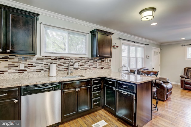 kitchen with sink, kitchen peninsula, dishwasher, a breakfast bar area, and light hardwood / wood-style floors