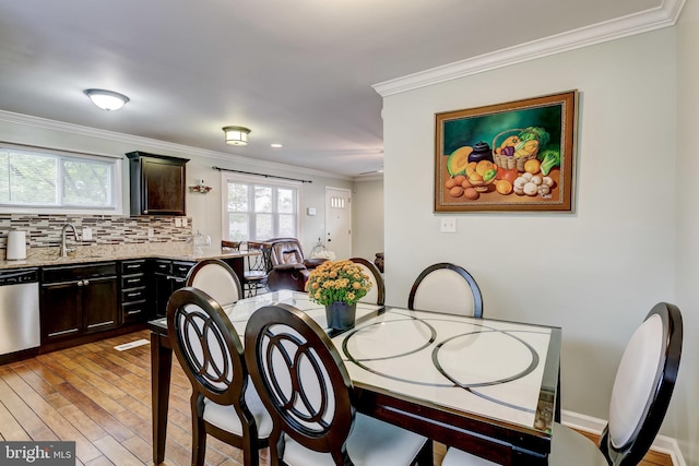 dining room with light hardwood / wood-style flooring, sink, and crown molding