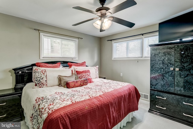 bedroom featuring multiple windows, light colored carpet, and ceiling fan