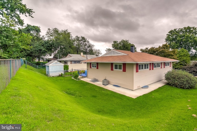 back of house featuring a yard, an outdoor structure, and a patio area