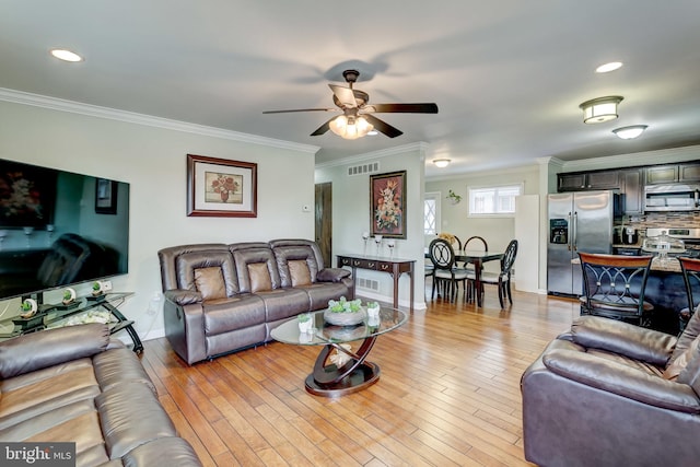 living room featuring light hardwood / wood-style floors, ornamental molding, and ceiling fan