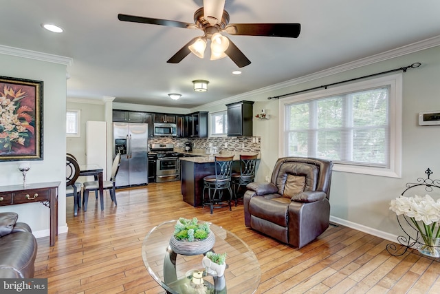 living room featuring ceiling fan, ornamental molding, and light hardwood / wood-style floors