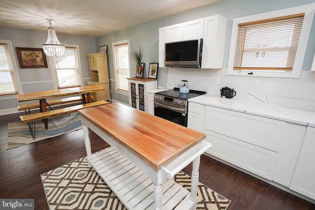 kitchen with stainless steel range with electric stovetop, pendant lighting, dark wood-type flooring, and white cabinetry