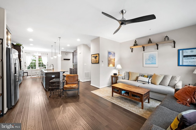 living room featuring ceiling fan, dark hardwood / wood-style floors, and sink