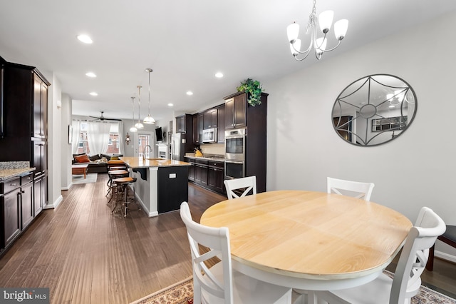 dining space featuring sink, a chandelier, and dark wood-type flooring