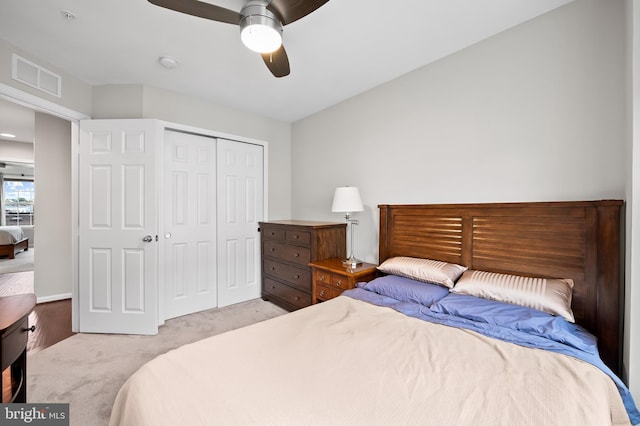 bedroom featuring a closet, light colored carpet, and ceiling fan