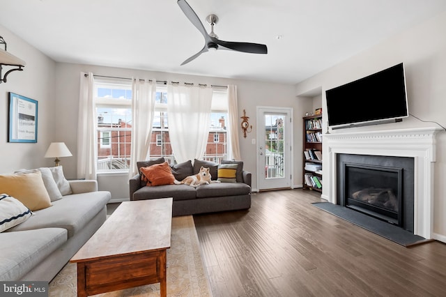 living room featuring ceiling fan, dark wood-type flooring, and plenty of natural light