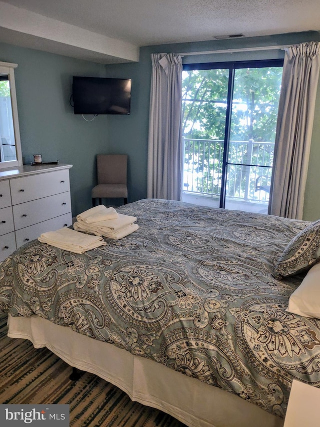 bedroom with a textured ceiling and access to exterior