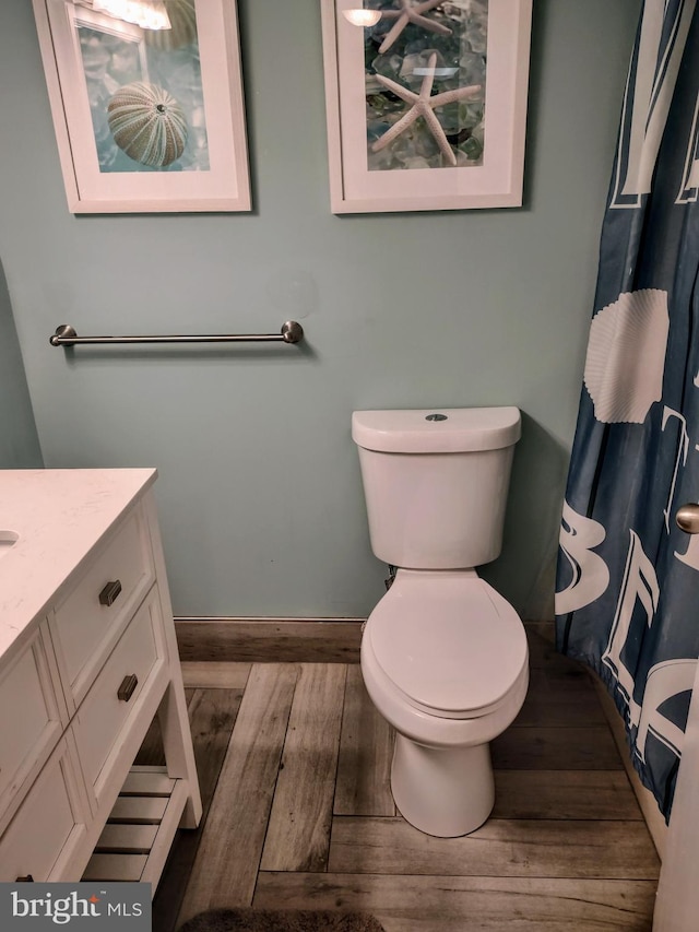 bathroom featuring walk in shower, hardwood / wood-style floors, vanity, and toilet