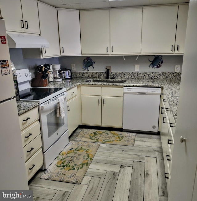 kitchen with light stone countertops, white appliances, light hardwood / wood-style flooring, and sink