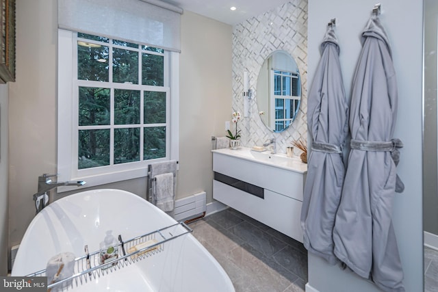 bathroom with vanity, a tub to relax in, and a baseboard radiator