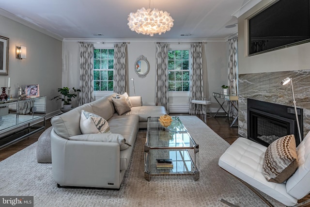 living room featuring ornamental molding, a notable chandelier, a fireplace, and dark wood-type flooring