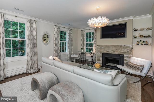 living room with an inviting chandelier, a premium fireplace, hardwood / wood-style floors, and crown molding